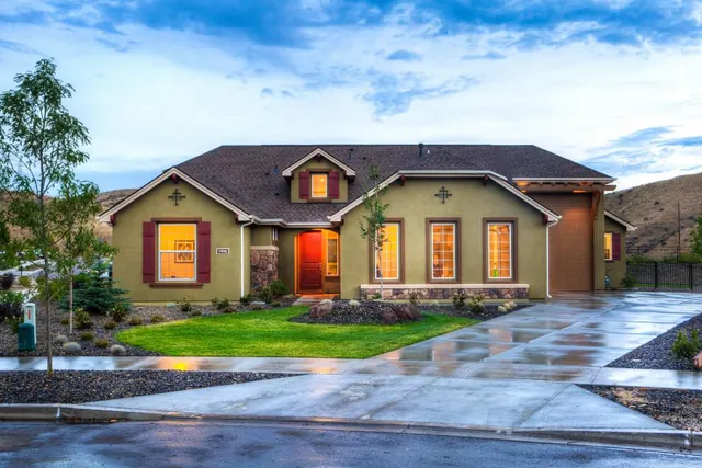 A suburban home at dusk with a clean lawn edge and a shrub bed along the driveway.